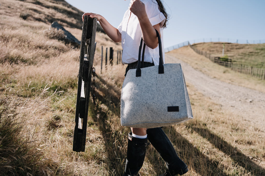Person walking outdoors with a gray Honest Wolf Casual Shopper tote bag holding a farm gate