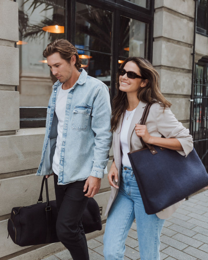Lifestyle image of people walking outdoors, one with a midnight Honest Wolf bag and the other with a navy blue Honest Wolf tote bag.