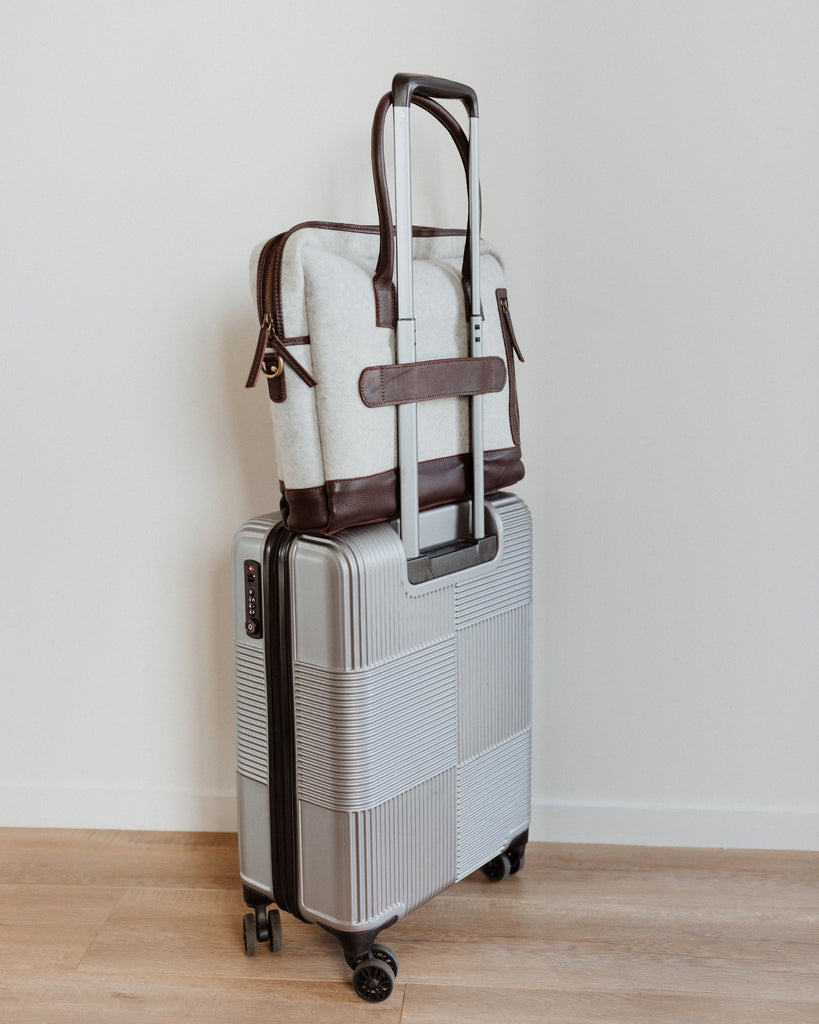 Honest wolf wool 
Satchel - Taupe, a view of the bag attached to the transport handle of luggage lifestyle